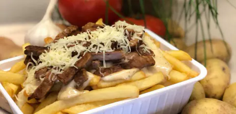 Friet met stoofvlees en geraspte kaas in een bakje