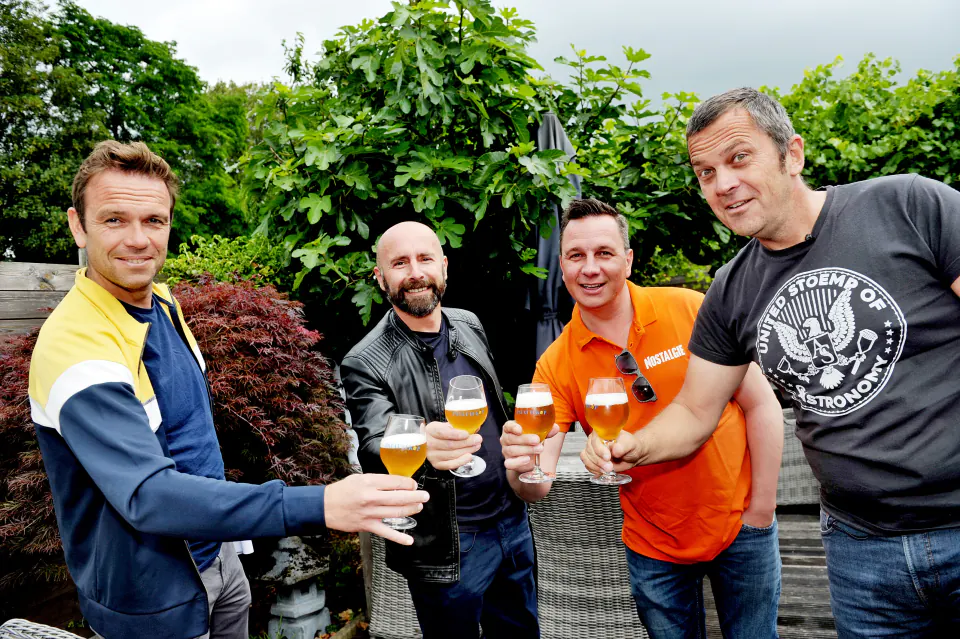 Vier mannen klinken met een glas Patattekop-bier in de tuin