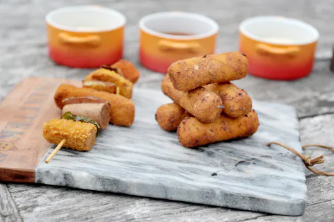 Patattekop kroketjes op een marmeren plank, met potjes saus